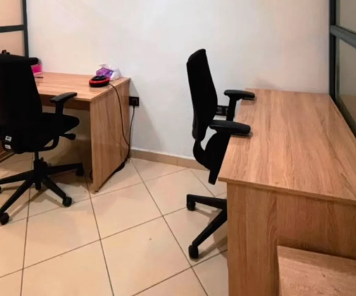 Un bureau privé de Leader Space avec deux bureaux en bois, deux chaises ergonomiques noires et une cloison vitrée